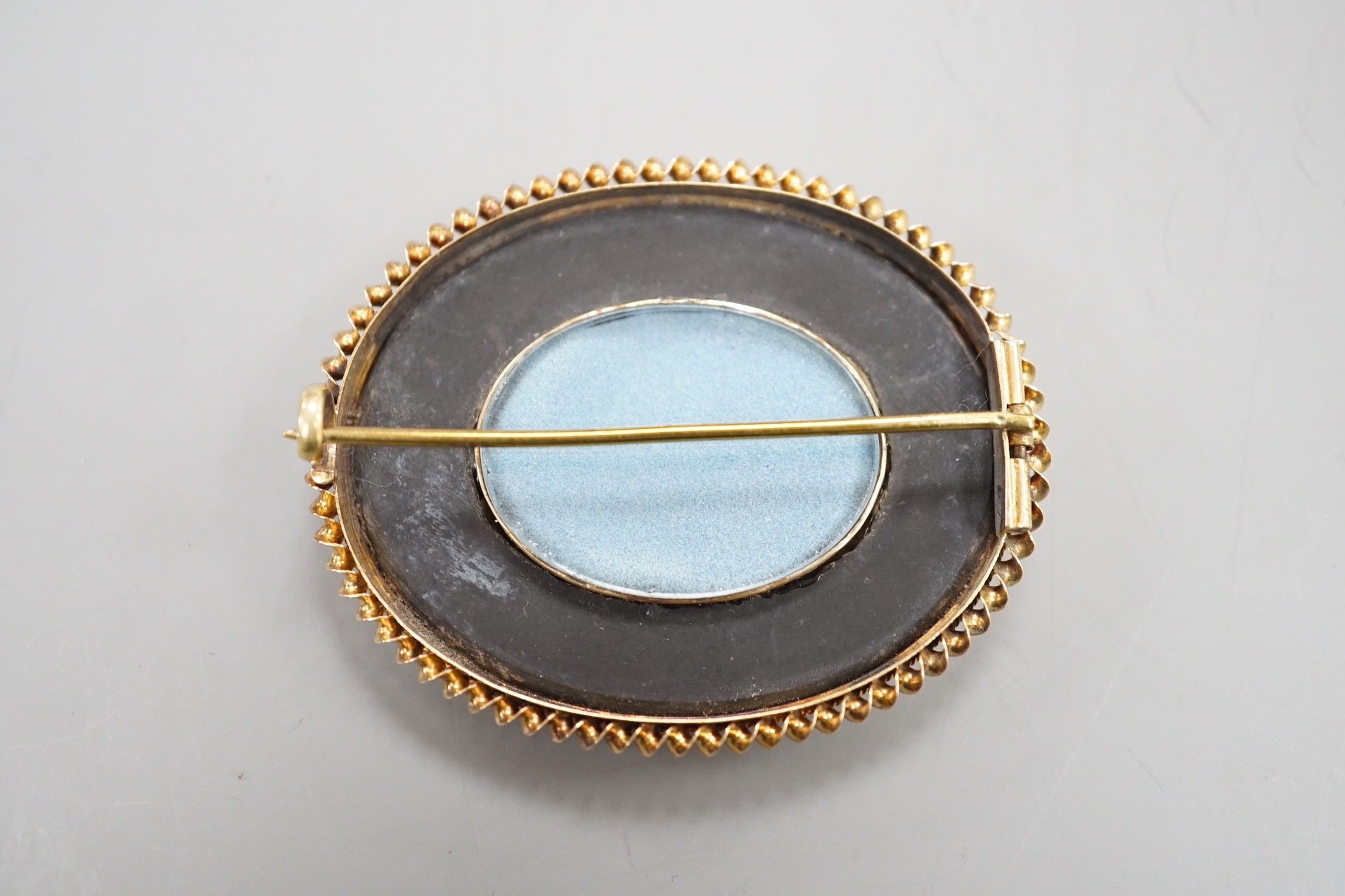 A late Victorian yellow metal mounted pietra dura oval brooch, decorated with a floral spray, 52mm.